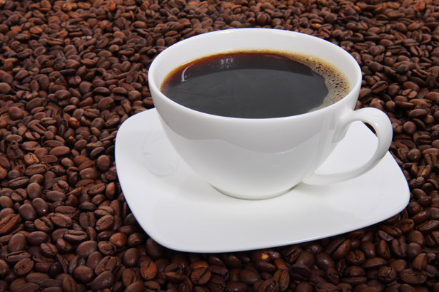 Kaffeetasse umgeben von Kaffeebohnen